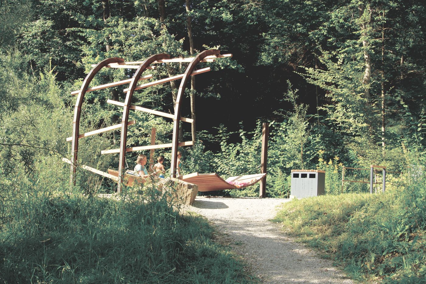 Hängematten und Skulptur aus Stahl und Holz an einem Waldweg