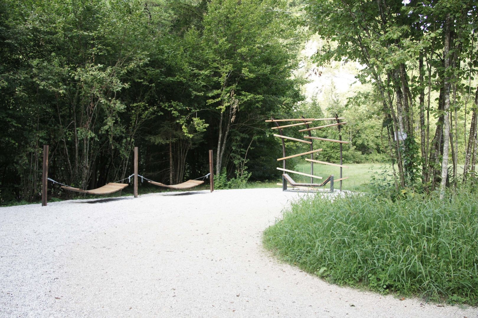 Hängematten und Skulptur aus Stahl und Holz an einem Waldweg